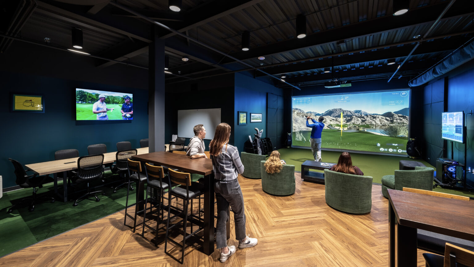 Entertainment lounge with high top tables and a golf simulator at the Zink Cincinnati center